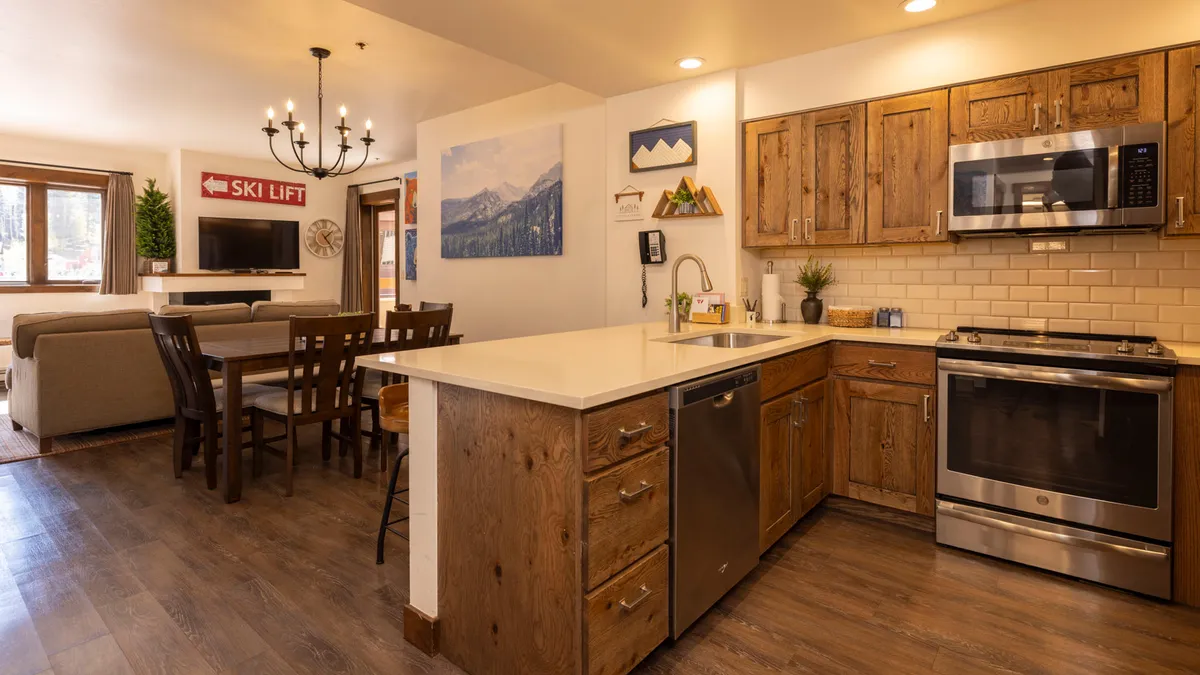 A spacious open-concept kitchen and dining area, with a kitchen island and a dining table positioned to enjoy the room’s natural light. Mountain artwork and cozy furnishings create an inviting, communal atmosphere perfect for group meals and conversation.
