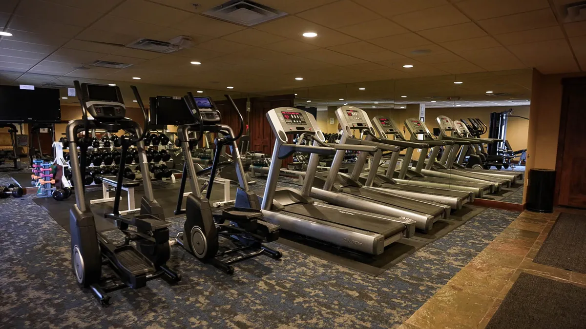 A modern fitness room outfitted with treadmills, ellipticals, dumbbells, and a mirrored wall. Bright and motivating, the space is perfect for both solo workouts and group exercise sessions, emphasizing wellness-focused amenities.